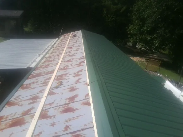 Old rusted panels beside newly installed green metal roofing — Wind Damage Roof Repair by Roofing Brothers in Wake Forest