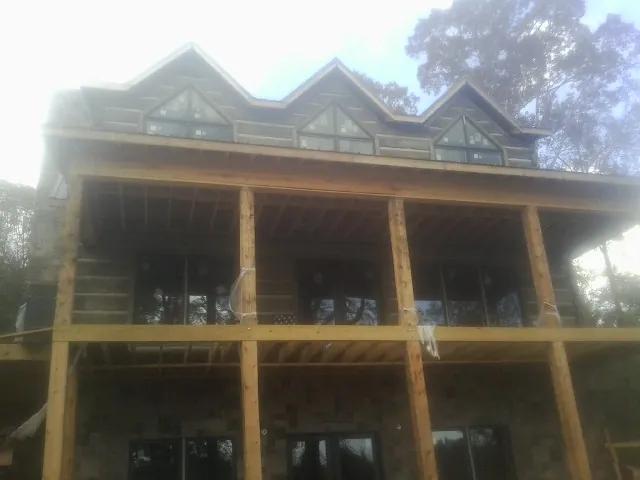 Dormers and porch framing on a large log home under construction — Roof Coating work by our crew in Wake Forest