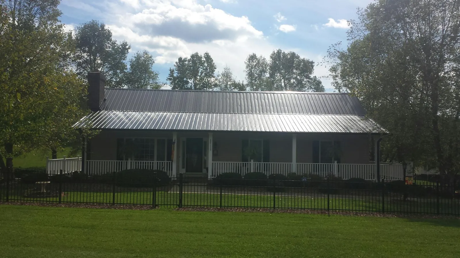 Gray metal roof on a brick ranch with a full width front porch — Gutter Guard Installation work by our crew in Wake Forest