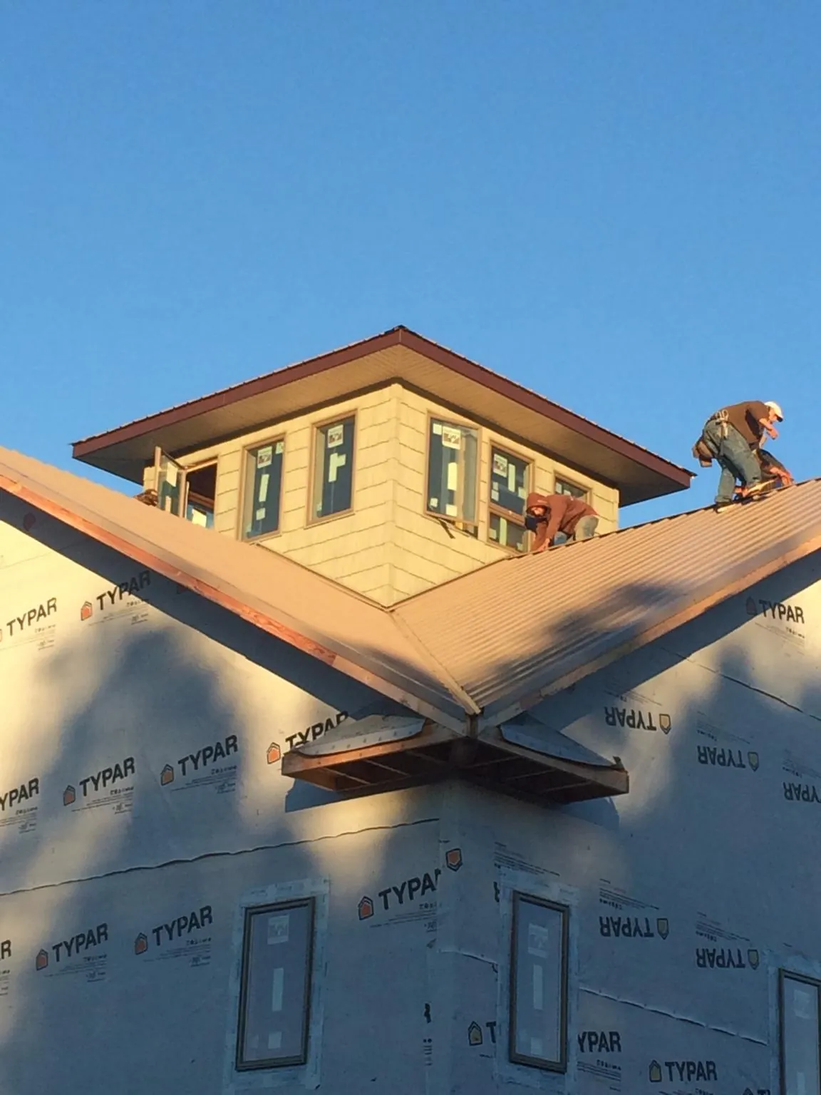 Roofers working around a rooftop cupola on a new metal roof at sunset — Roof Waterproofing in Wake Forest by Roofing Brothers